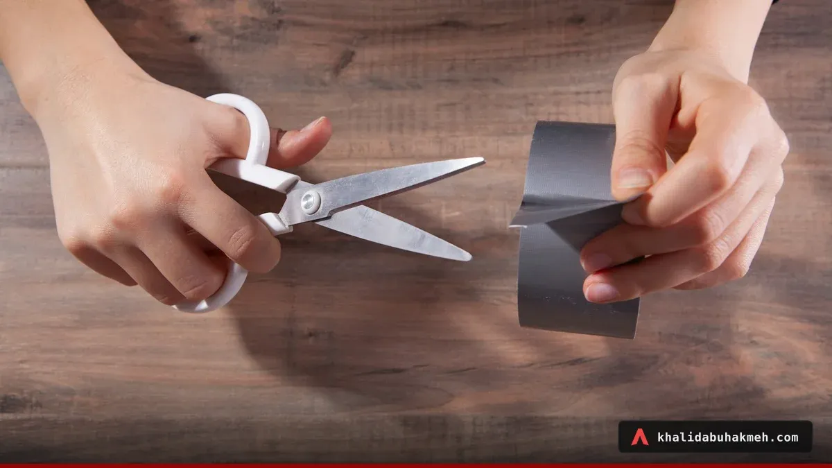 Hands cutting a strip of grey duct tape with scissors, improvising a quick fix. Photo by Sasun Bughdaryan on Unsplash.